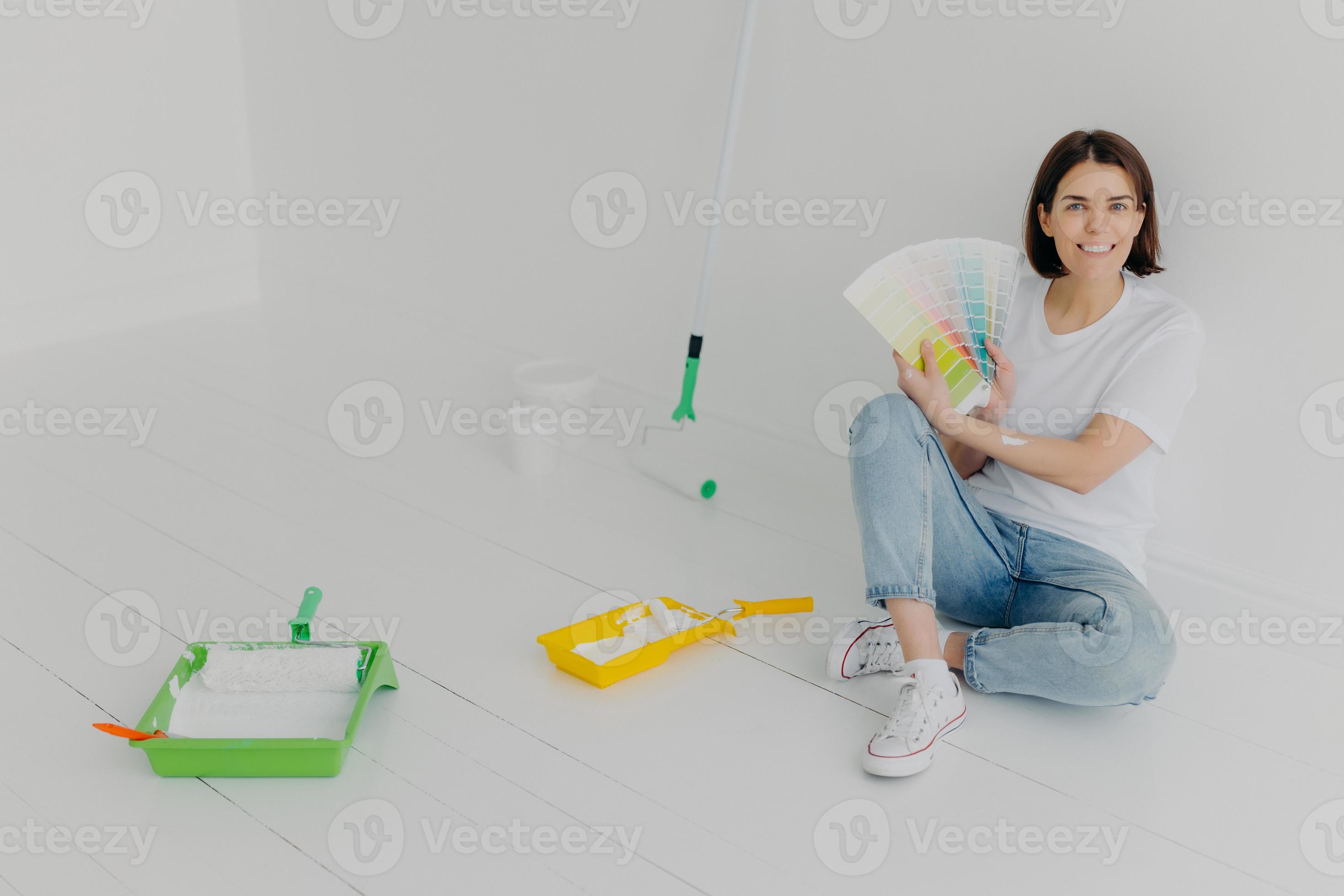Glad Brunette Woman Demonstrates Color Samples Dressed In White T Shirt And Jeans Chooses Tone