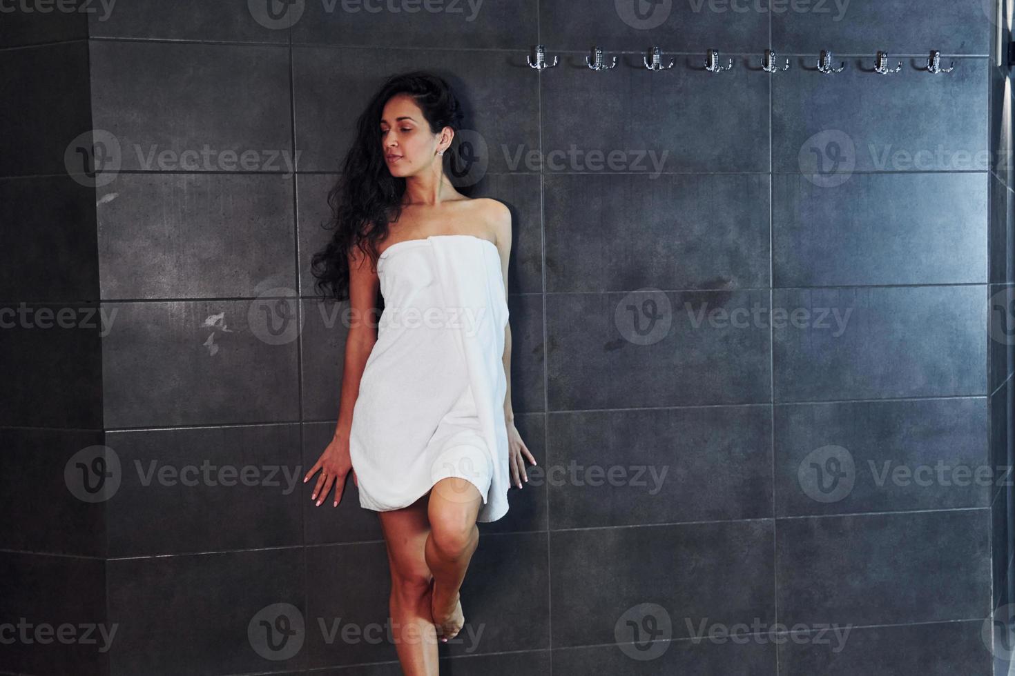 Pretty Brunette With Slim Body Type In White Towel Standing In Spa Shower Stock Photo