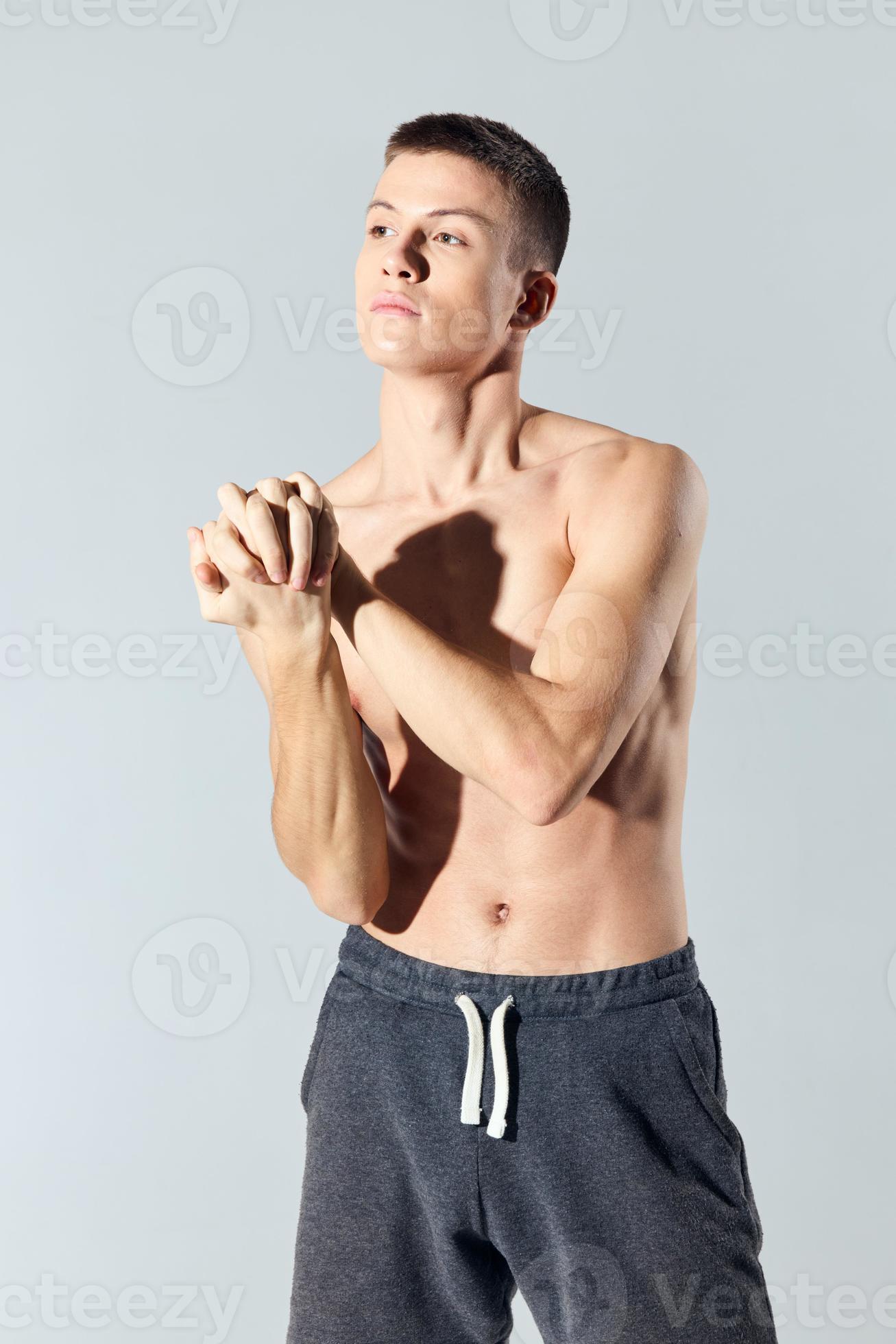 A Naked Athlete In Shorts On A Light Background Gestures With His Hands Biceps Muscles