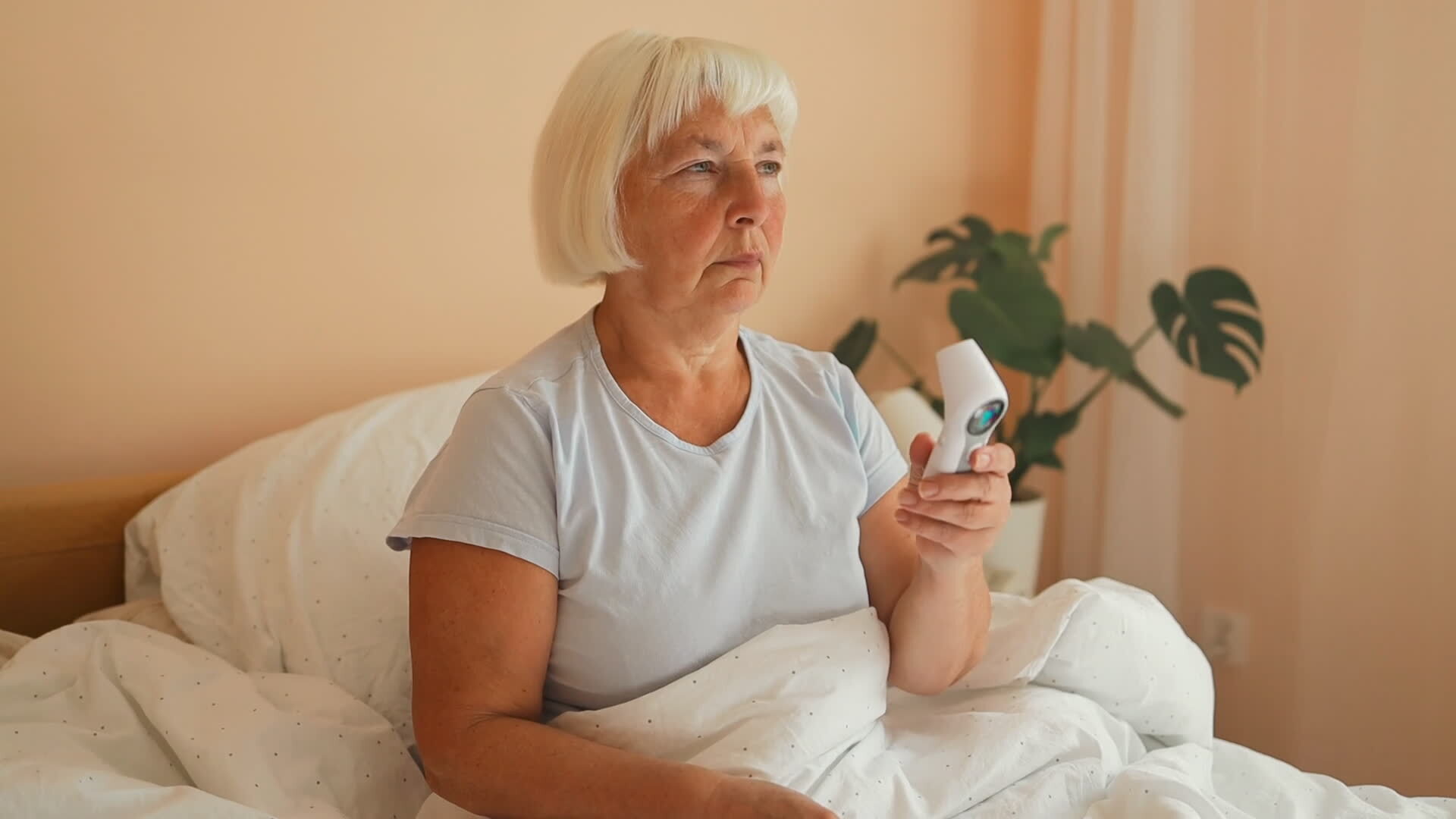 Mature Woman Lying In Bed Reading Temperature From Thermometer Healthcare And Medical Checking