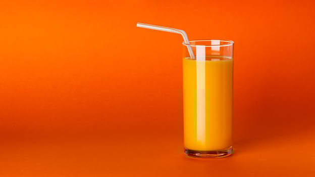 A glass of orange juice on orange background with copy space photo
