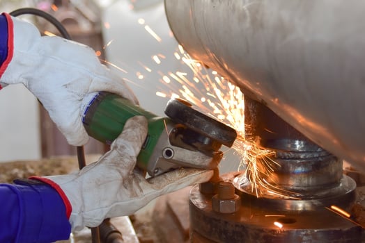 Worker grinds steel pipe photo