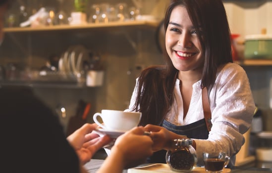Beautiful barista serving hot coffee to customer photo