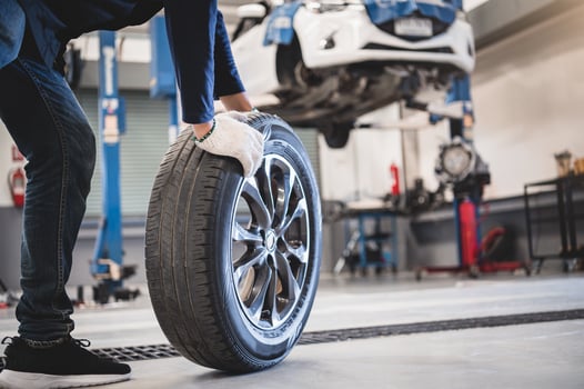 Male mechanic rolling tire photo