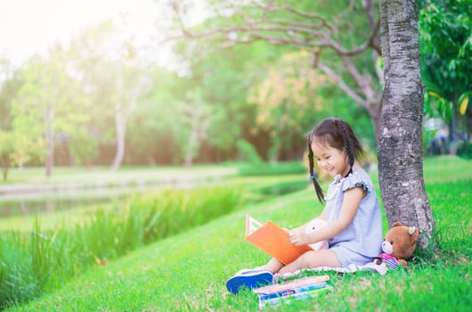 Young Asian girl reading book in a park photo