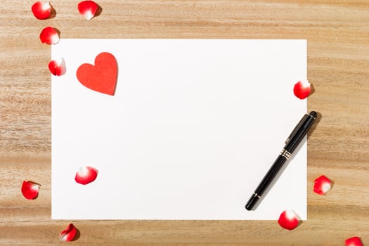 Top view of paper with a pen and red petals photo