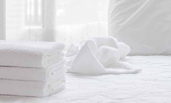 Folded clean towels on a white bed sheet photo