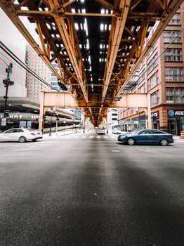 Cars speeding by under a brown metal bridge photo