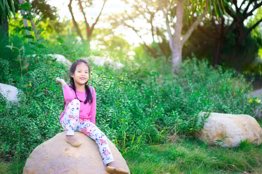Happy Asian girl sitting on the rock with sunlight photo
