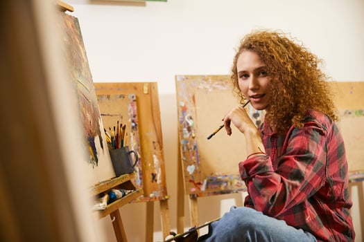 Portrait of beautiful redhead curly artist with brush during her work photo