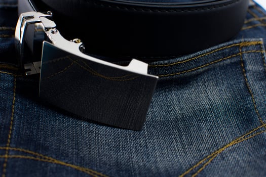 Detail of jeans with black leather belt close-up photo