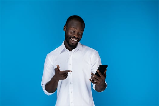 A smiling man looking at his phone photo