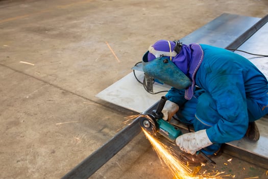 Worker in blue uniform cutting metal sheets photo