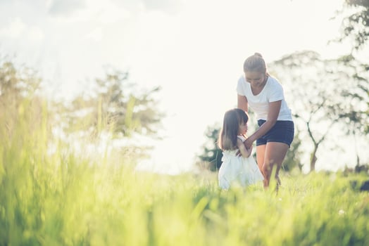 Mother and little daughter playing together in a meadow photo
