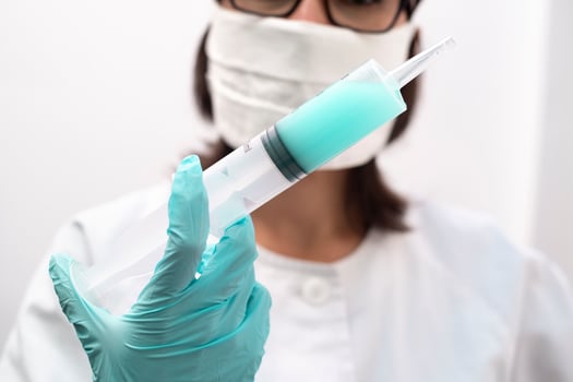 Nurse wearing a mask and gloves holding a syringe photo