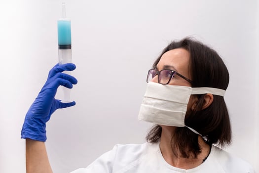 A nurse wearing a mask and gloves holding a syringe of virus vaccine in a modern clinic photo