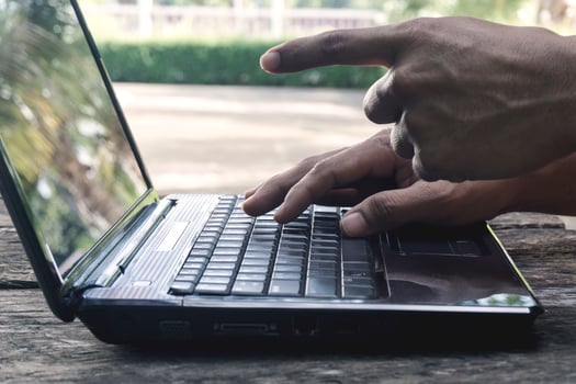 Hand Person working pointing to screen and using on a laptop computer for freelance with input keyboard for online blogger job to black computer on a wooden table at home. photo