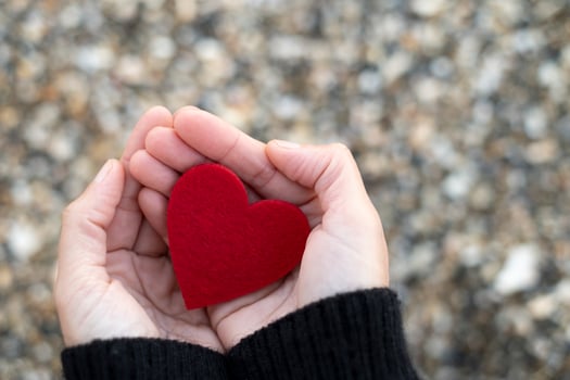 Red heart between the hands of a woman on a background of beach stones.concept of san valentin photo