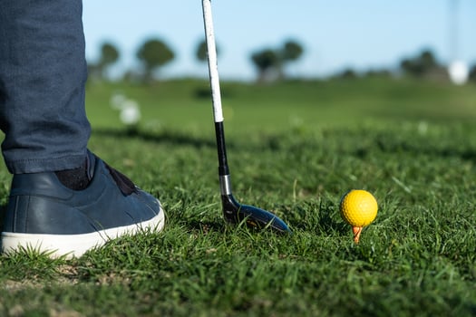 Close-up of shoes, golf club, and golf ball on a driving range photo
