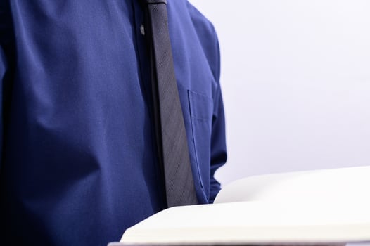 A man in a blue shirt and tie holding a book photo