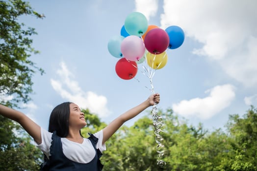 Young girl holding colorful balloons in nature photo