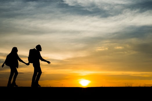 Silhouettes of two hikers with backpacks enjoying the sunset photo
