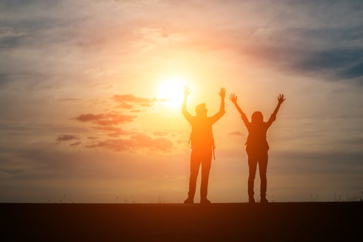 Silhouettes of two hikers with backpacks enjoying the sunset photo