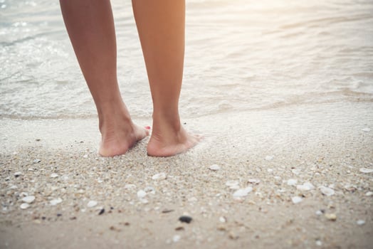 Young woman standing on the beach with bare feet photo