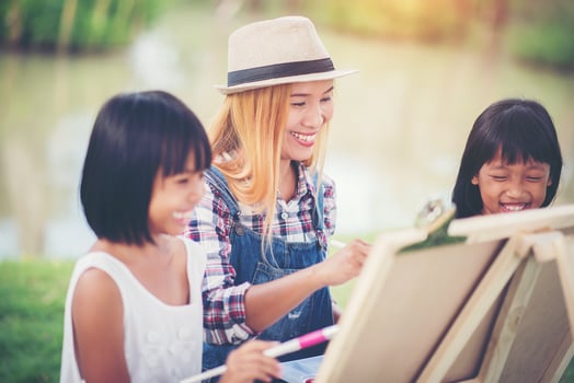 Mother and daughters drawing pictures together in a park photo