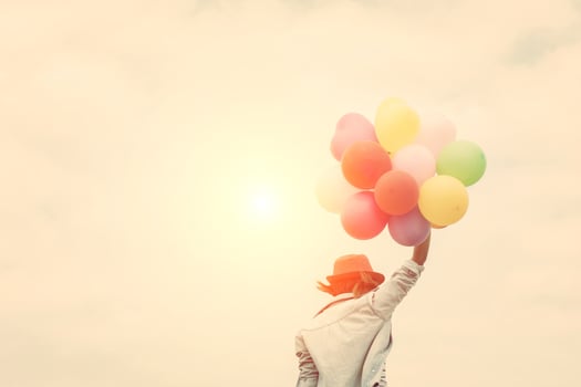 Beautiful young woman holding balloons at the beach photo