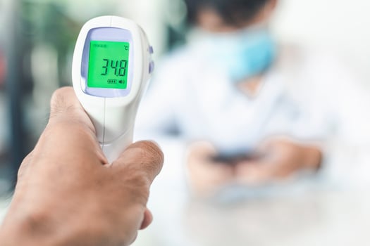 Person taking temperature of blurred person photo