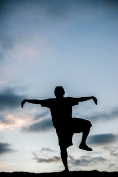 Silhouette of young man doing yoga at sunset photo