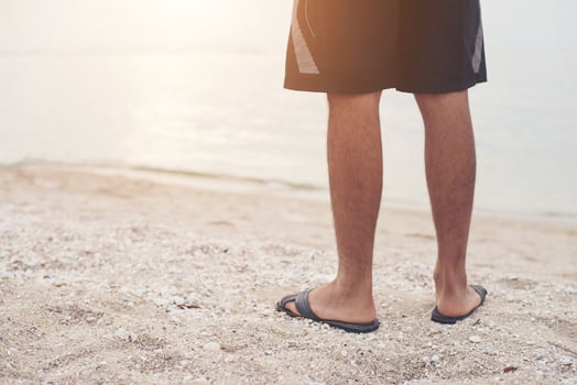 Young man's legs in sandals on the beach photo