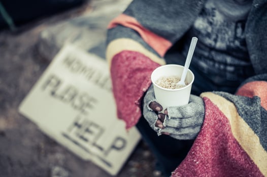 Homeless man wrapped in cloths and eating noodles photo