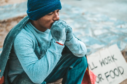 A man sits begging with homeless please help message photo