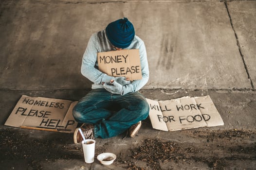 Beggar sitting under the overpass with a please help sign photo