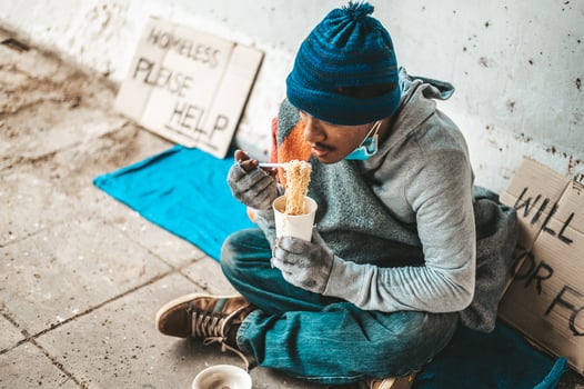 Homeless man wrapped in cloth and eating noodles photo