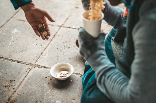 Beggar sitting under a bridge with cup of money and noodles photo