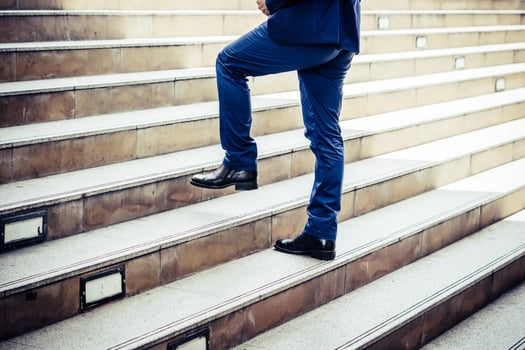 Close-up of young businessman walking upstairs outside office photo