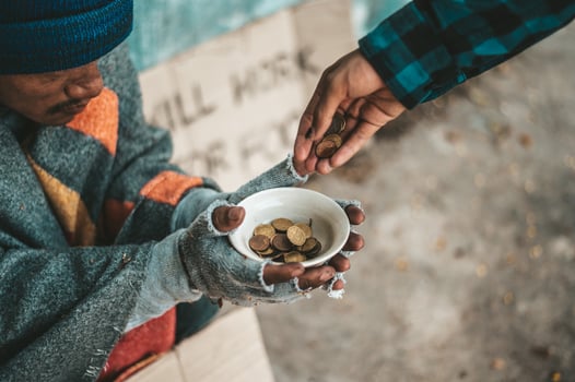 Person gives to a beggar on the side of the road photo