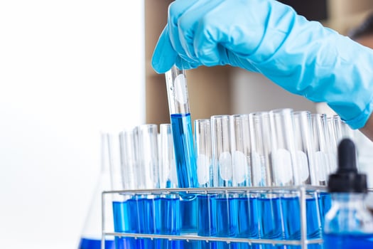 Scientist with gloves looking at test tubes photo