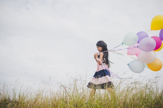 Little girl playing with balloons on meadows field photo