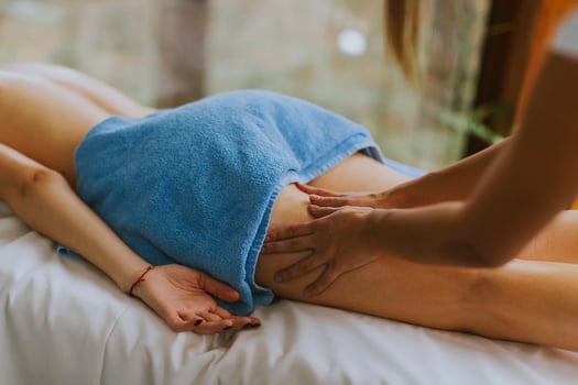 Beautiful young woman lying and having leg massage in spa salon during winter season photo