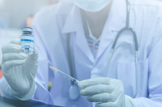 A male doctor holding a bottle of the COVID-19 or the coronavirus vaccine and a syringe photo