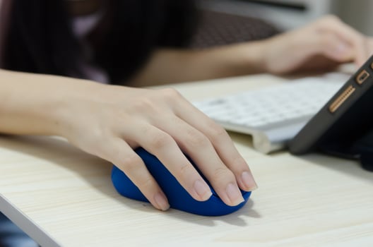 A girl's hand holding a blue computer mouse photo