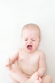 Cute baby girl crying on bed photo