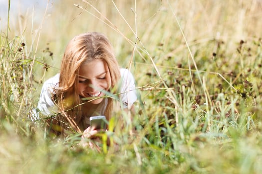 Girl with a phone laying in the grass photo