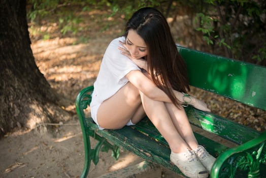 Sad lonely woman sitting on a bench alone at the park photo