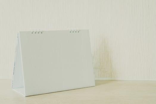 Blank white calendar on wooden background photo