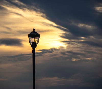 A lamppost silhouetted at sunrise in a cloudy sky photo